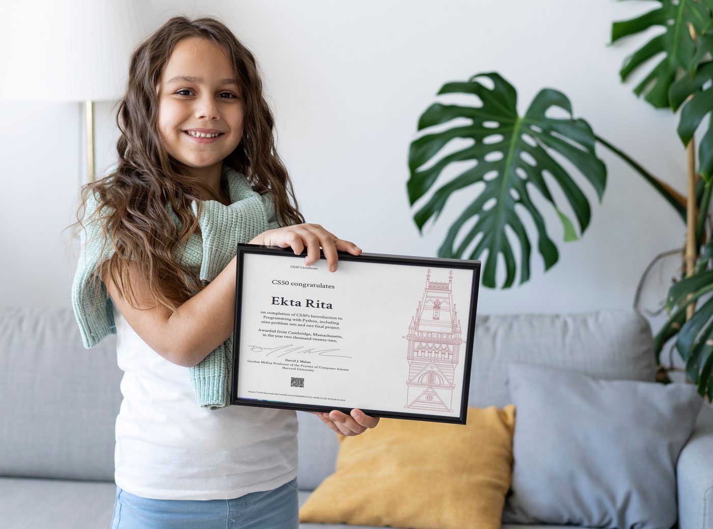 A proud young Techmentry student holding her framed Harvard CS50 certificate