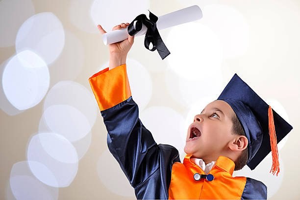 A young Techmentry student in graduation gown celebrating with his diploma